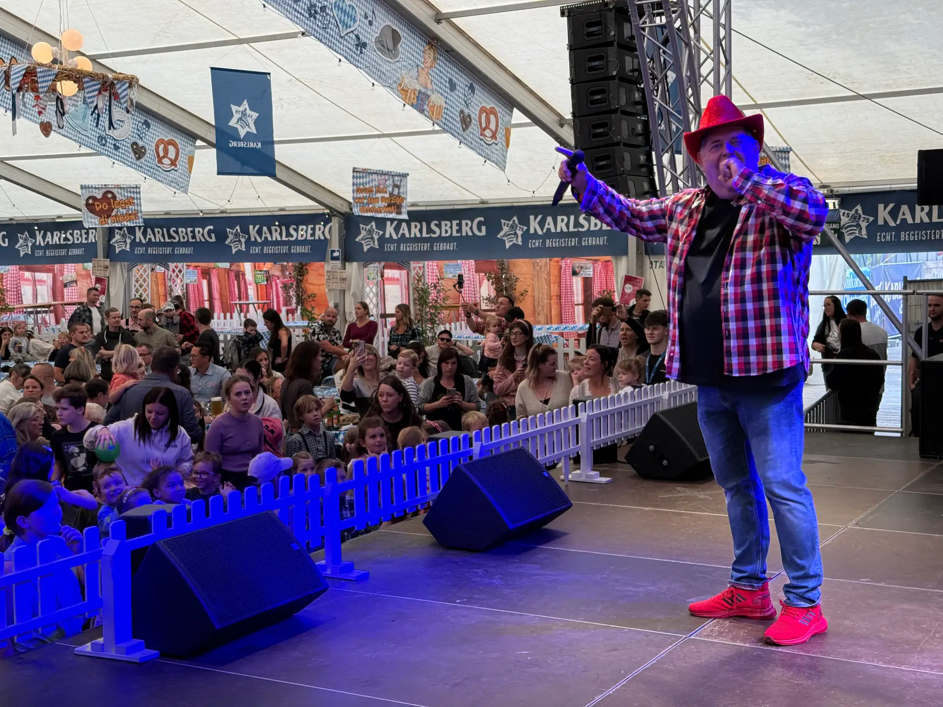 Zwei Personen stehen auf einer Bühne und wirken wie bei einer Veranstaltung für Kinderoktoberfest.